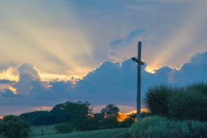 A cross surrounded by sunlight bursting through clouds